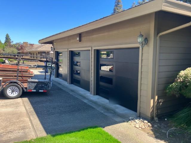 Black flush steel garage doors with four stacked windows on each door at a Modesto home