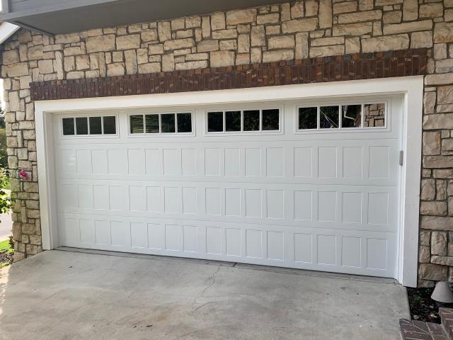 Finished white shaker-panel garage door framed by stone in Danville