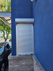 Pentagon aluminum shutter door installed at a Dutch Bros drive-through window
