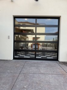 Exterior view through the glass garage door toward the vehicle and garage interior