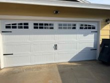 White long-panel carriage-house garage door with Stockton and Arched Stockton windows and black strap hinges