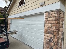 White short raised-panel double garage door beside a stone-veneer pillar at an Oakdale home