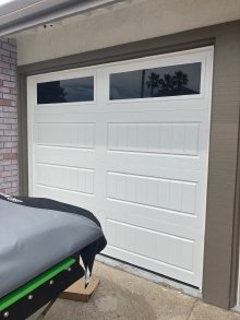 White single garage door with two rectangular top windows and grooved carriage-house panels in Discovery Bay
