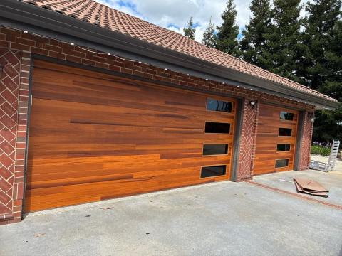 Wood-look plank garage doors with stacked dark windows on a Lodi brick home