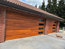 Double and single wood-look plank garage doors with stacked dark-glass windows on a Lodi brick home