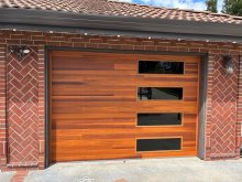 Close view of the single wood-look garage door with four stacked windows between brick pillars