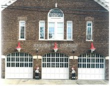 Three white arched full-view sectional doors on a brick fire station