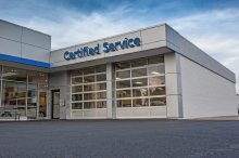 Two white aluminum full-view sectional doors on a car dealership service entrance