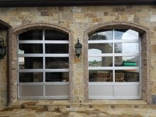 Pair of silver full-view glass sectional doors in arched stone openings