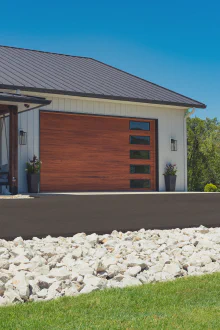 Cedar-tone CHI Skyline Flush garage door with vertically stacked windows on a modern white home