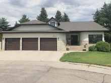 Walnut-tone CHI Planks garage doors with one stacked-window door on a white stone-accented home