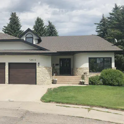 Walnut-tone CHI Planks garage doors with one stacked-window door on a white stone-accented home