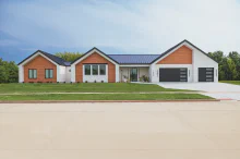 Black CHI Skyline Flush garage door with stacked obscure windows on a modern white-and-wood exterior