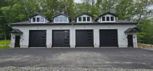 Four black CHI Skyline Flush garage doors with stacked windows on a white multi-bay garage