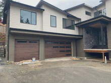 Dark oak CHI Skyline Flush garage doors with offset StyleLite windows on a contemporary home