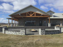 Black-framed CHI full-view glass garage door on a stone-and-timber entertainment pavilion