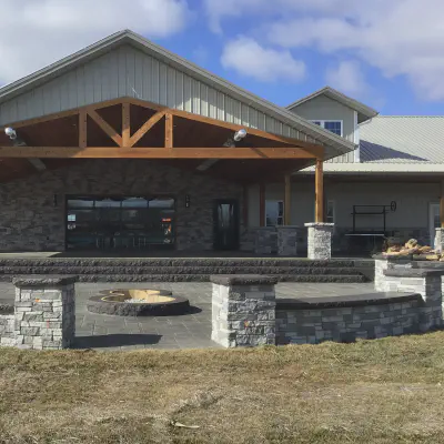 Black-framed CHI full-view glass garage door on a stone-and-timber entertainment pavilion