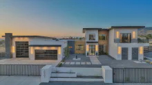 Black-framed CHI full-view glass garage doors on a contemporary home at dusk