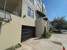 Black CHI full-view glass garage door on a modern urban residence