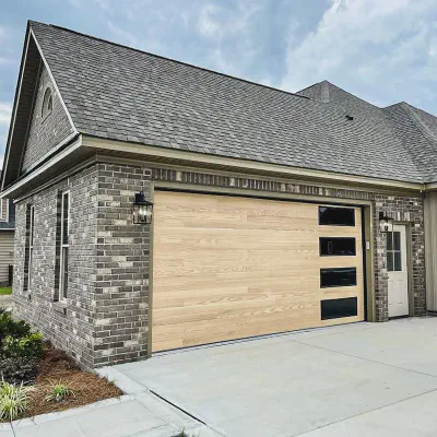 Natural oak CHI Planks garage door with vertically stacked windows on a brick home