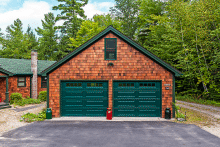 Twin evergreen raised panel garage doors with rectangular window lites on a cedar shake home