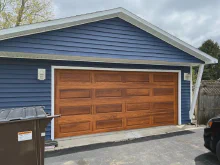 Cedar-tone CHI long raised-panel garage door on a blue home