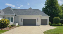 Graphite CHI short raised-panel garage doors on a white brick home