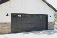 Black CHI recessed short-panel garage door with top-row windows on a white farmhouse-style exterior