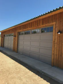 Sandstone CHI recessed long-panel garage door with Madison windows on a wood-sided garage