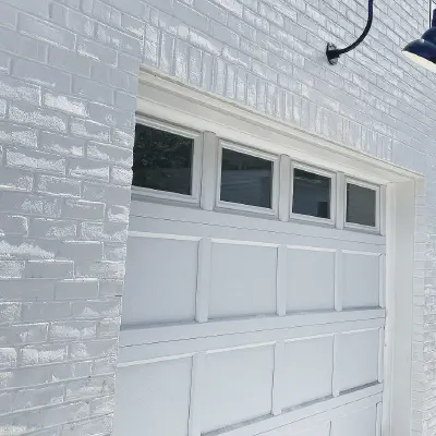 White CHI recessed short-panel garage doors with top-row windows on a white brick home