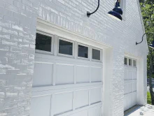 White CHI recessed short-panel garage doors with top-row windows on a white brick home