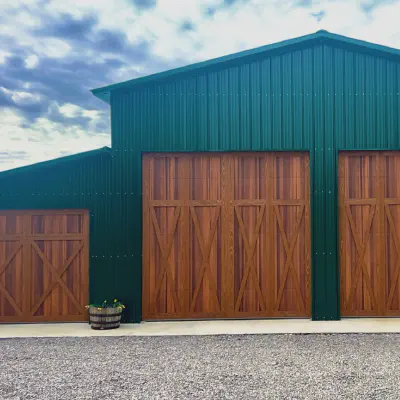 Cedar-tone CHI Shoreline overlay doors with vertical windows on a green barn