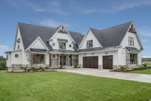 Two-tone CHI Shoreline garage doors with Madison windows on a large white home