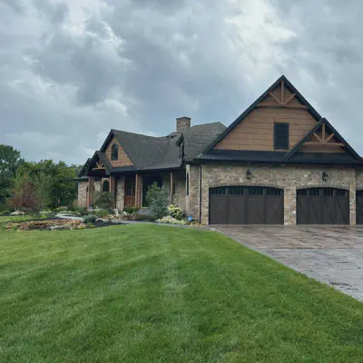 Walnut-tone CHI Shoreline overlay garage doors on a stone-and-timber lodge
