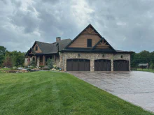 Walnut-tone CHI Shoreline overlay garage doors on a stone-and-timber lodge