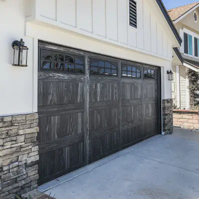 Carbon oak CHI Stamped Carriage House garage door with arched windows on a white home