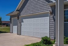 White C.H.I. stamped carriage house garage doors with recessed carriage panels on a gray home