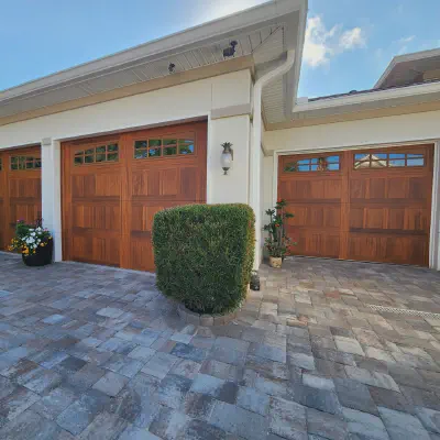 Cedar-tone CHI Stamped Shaker garage doors with top-row windows on a stucco home