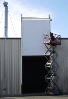 Technician on scissor lift inspecting a tall fumigation-room door